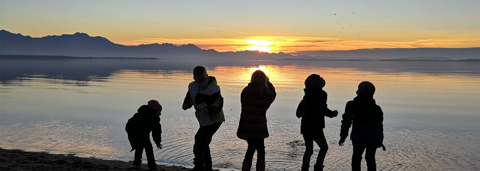 Kinder im Winter am See bei Sonnenuntergang